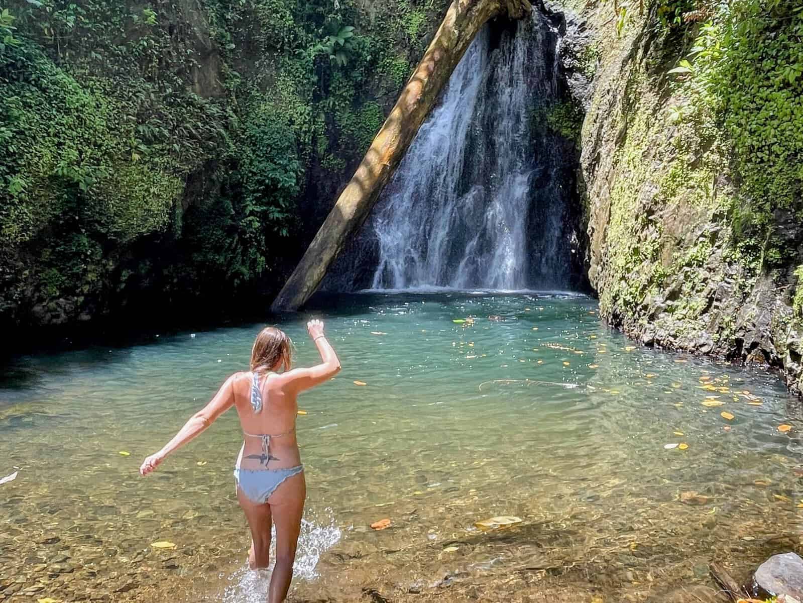 Girl entering the natural pool at Seven Sisters Waterfall in Grenada