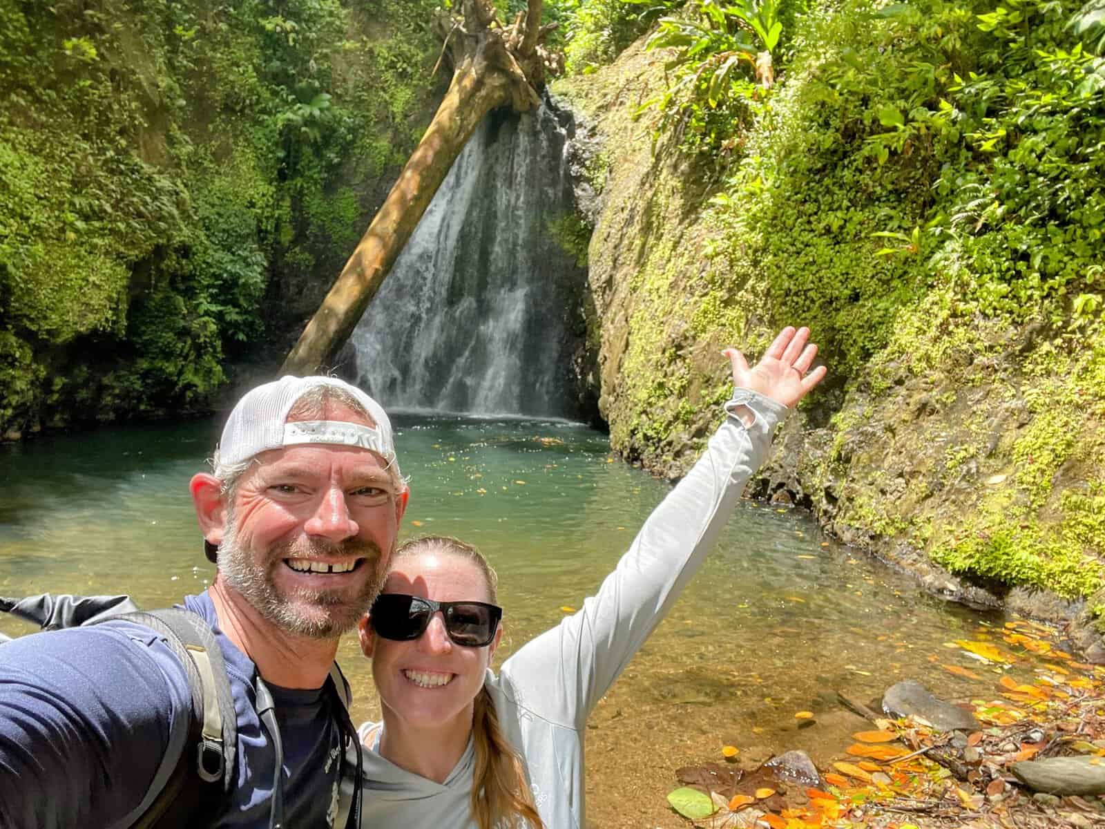 Joe and Mandy of Waves and Wander standing in front of Seven Sisters Waterfall in Grenada