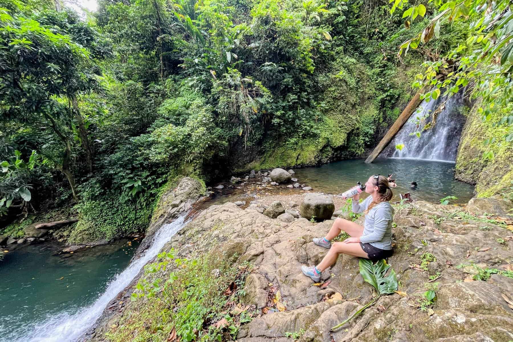 Girl drinking water between the two falls at Seven Sisters Waterfall in Grenada