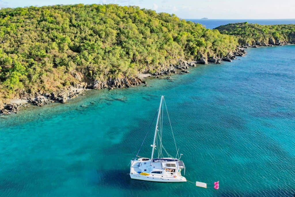 charter sailboat with water toys anchored in Caribbean turquoise waters with green island in background