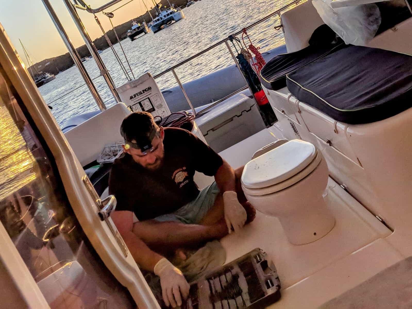 captain fixing broken toilet in cockpit of a charter sailboat in the Caribbean