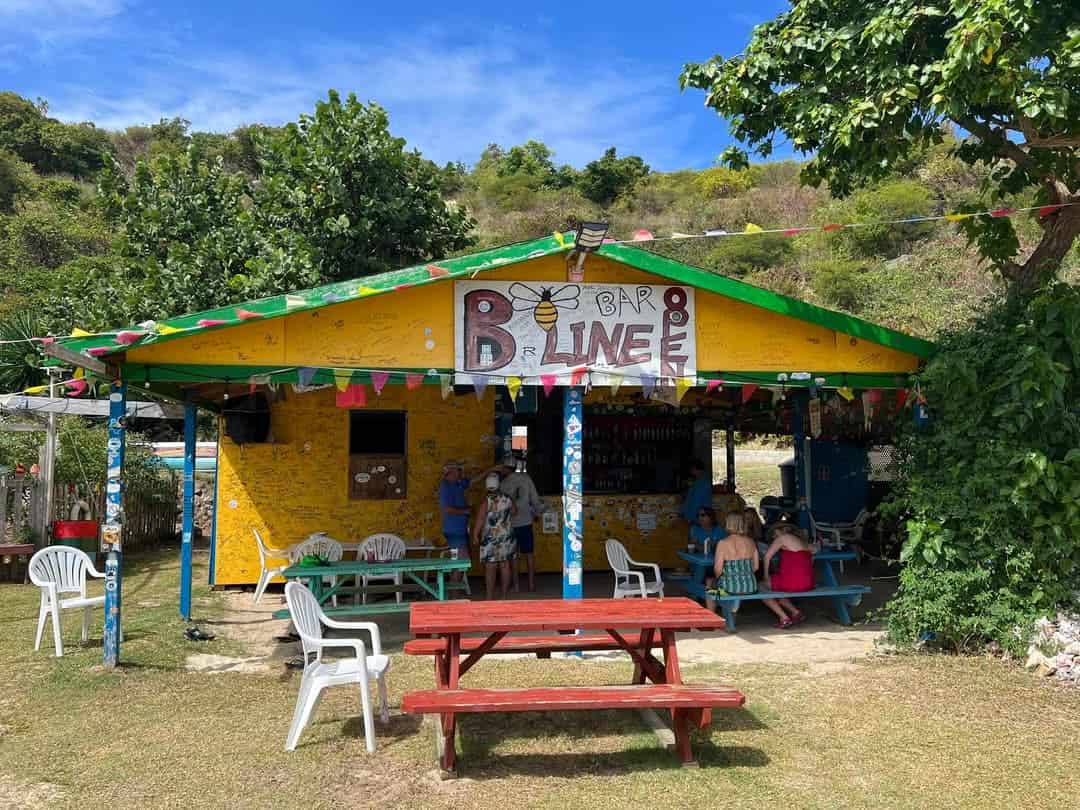 B-line bar a colorful wooden structure with picnic tables and people under shaded area on Little Jost Van Dyke, BVI