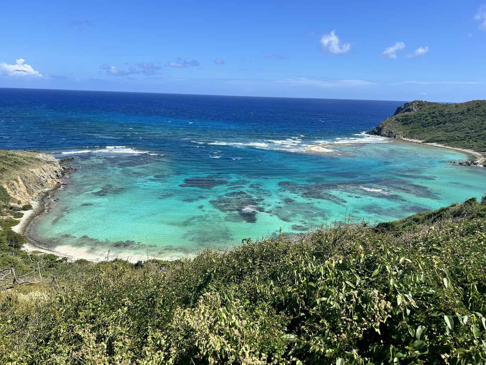 Aerial view of Money Bay on Norman Island in the BVI showing many shades of the bright blues of the ocean