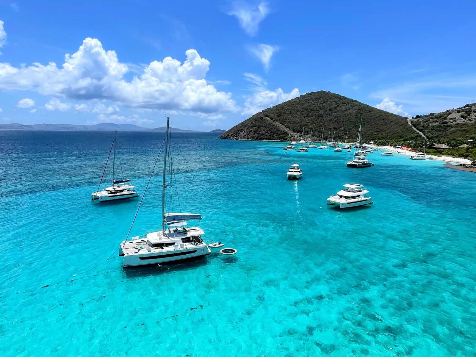 White Bay, Jost Van Dyke, British Virgin Islands. Catamarans floating in bright turquoise water with beach and green hills in background