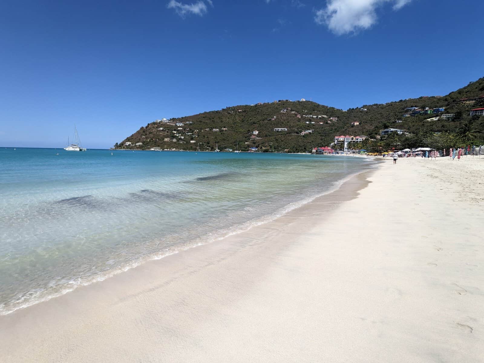 Cane Garden Bay, Tortola, British Virgin Islands. Teal ocean along wide beach with green hills in background