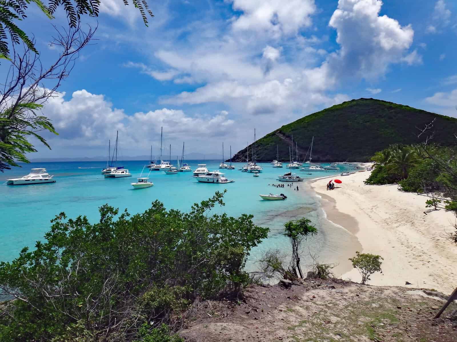 Boats floating in White Bay, Jost Van Dyke, British Virgin Islands. sandy beach green bushes and hillside. 