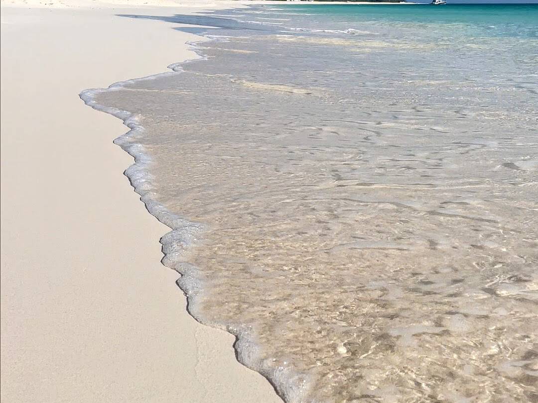 Clear ocean water lapping on to white sand beach