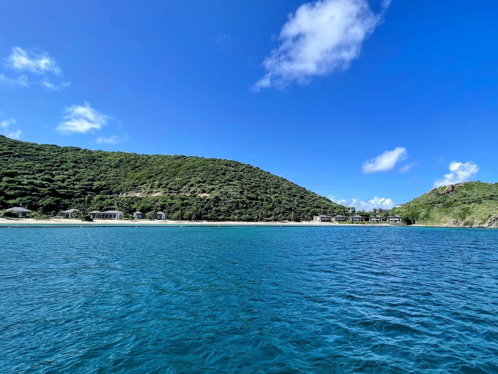 Deadman's Beach, Peter Island, British Virgin Islands. Blue ocean, green hills with shite sand beach and villas.