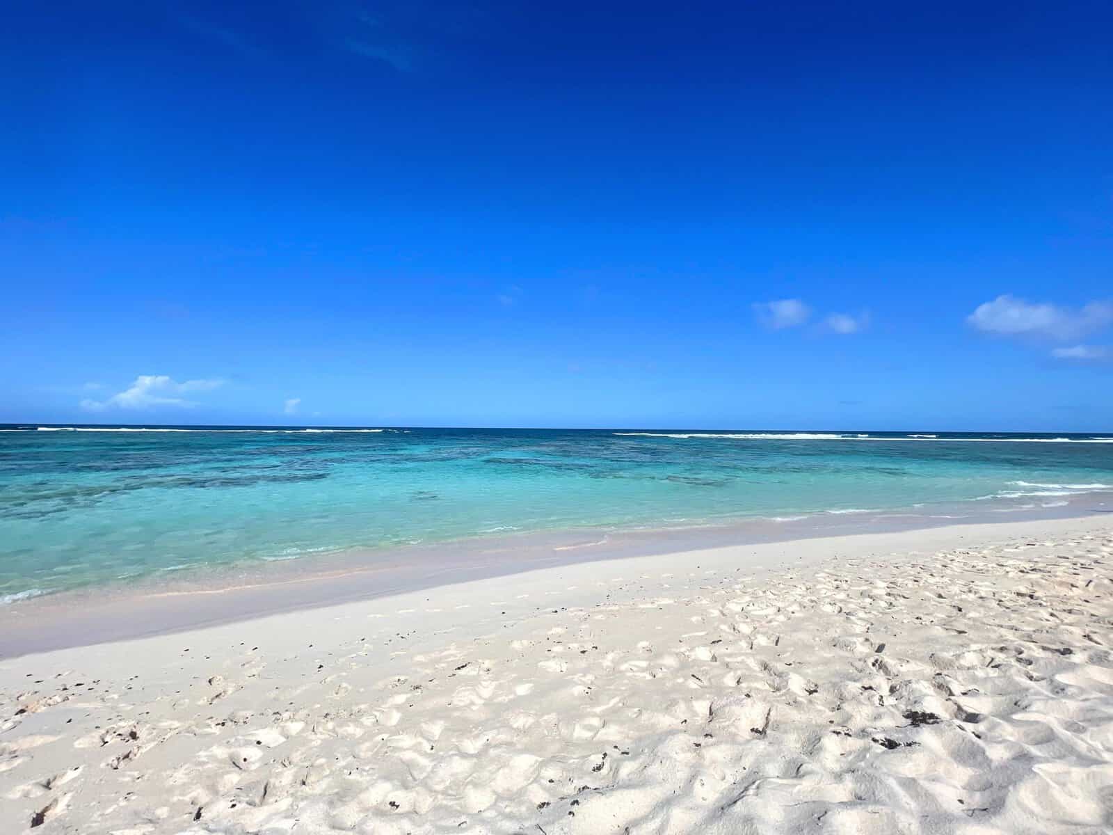 Loblolly Beach, Anegada, British Virgin Islands. Bright blue sky, many shades of teal blue water, and white sand beach