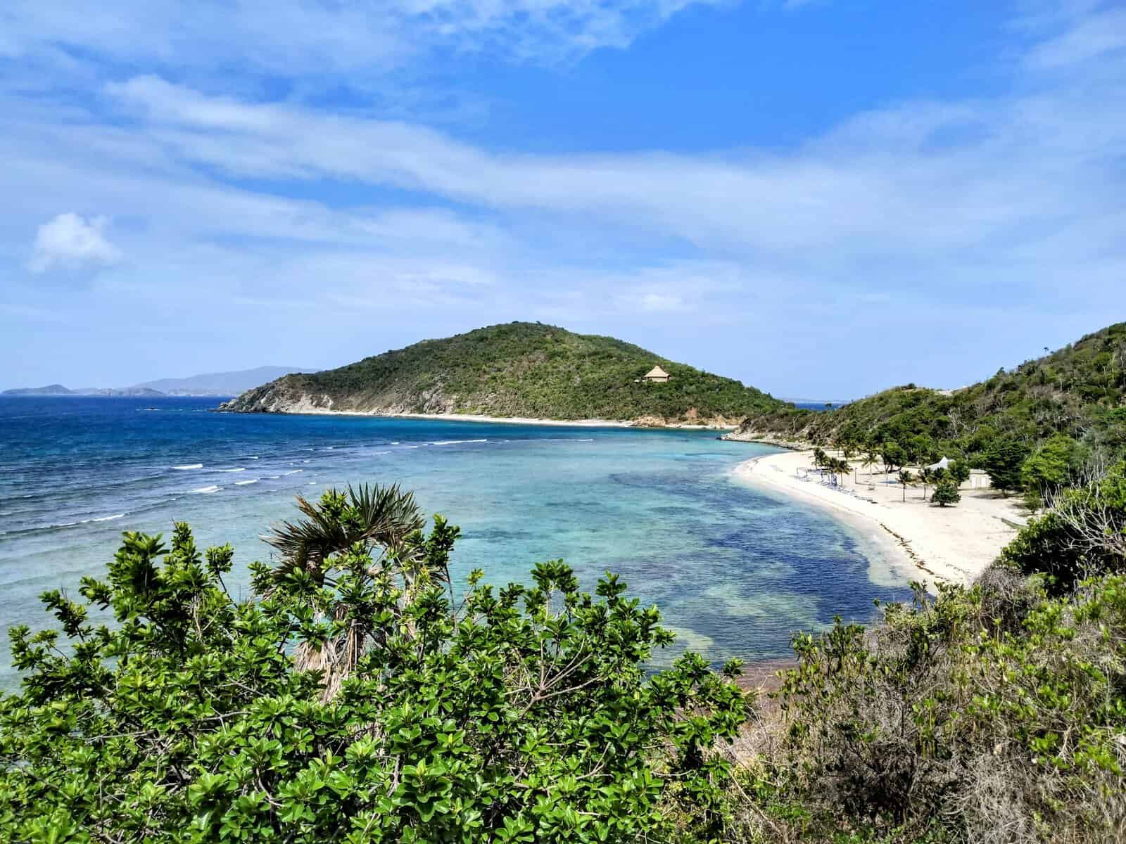 North Bay, Scrub Island, British Virgin Islands blue ocean with submerged coral reef, sand and palm tree and green hills
