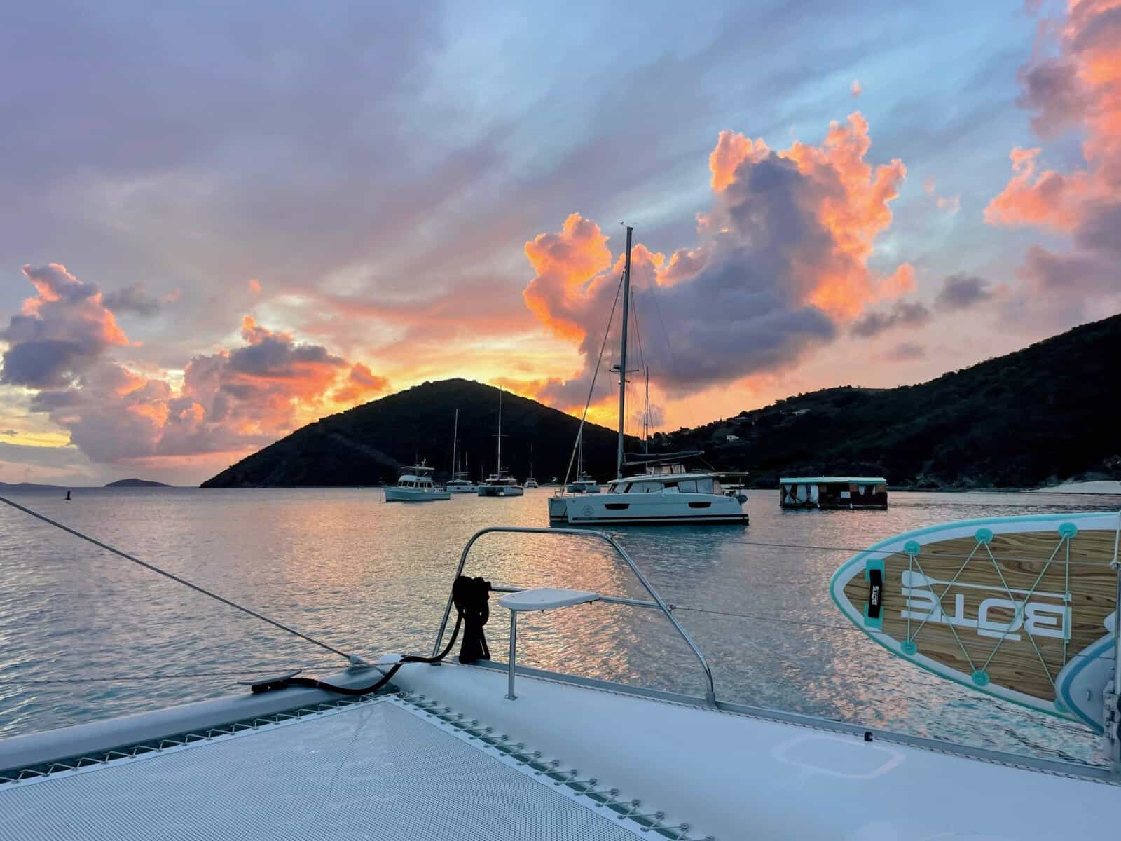 sunset behind Jost Van Dyke, British Virgin Islands with catamarans floating in White Bay