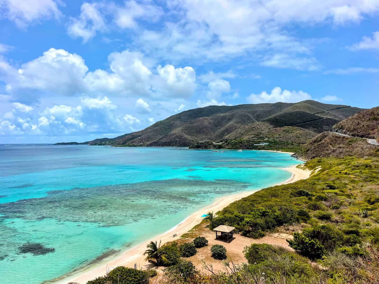 Savannah Bay, Virgin Gorda, British Virgin Islands, with teal waters, submerged reef, long beach, green brushes and hillside.