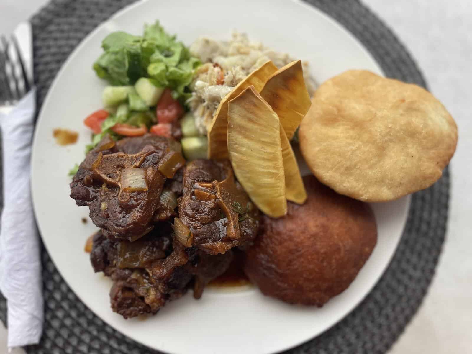 Plate of food: oxtail, plantain chips, and Johnny cakes from the British Virgin Islands