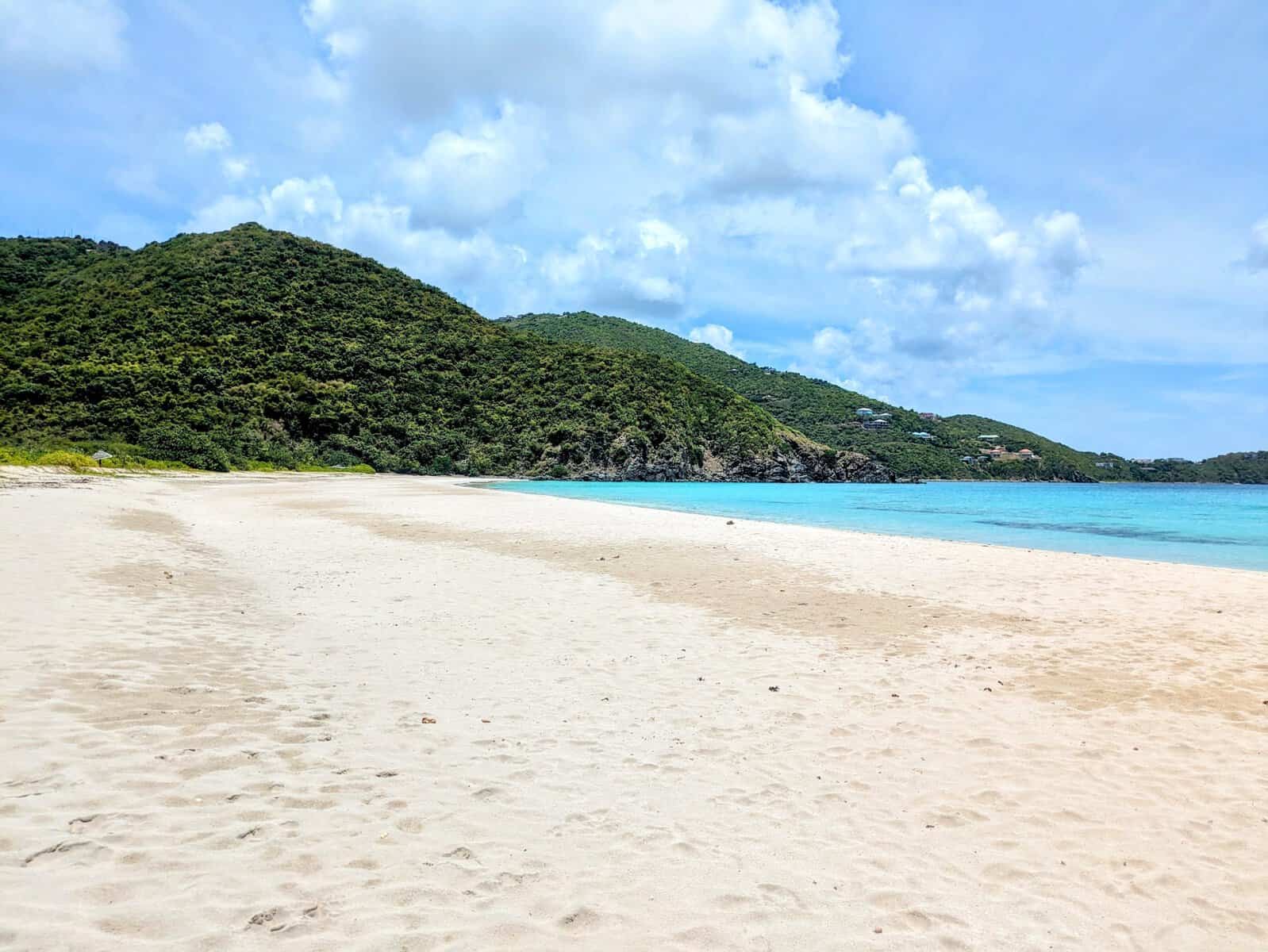 Josiah's Beach on Tortola, large white sand beach with teal blue with green hills in background