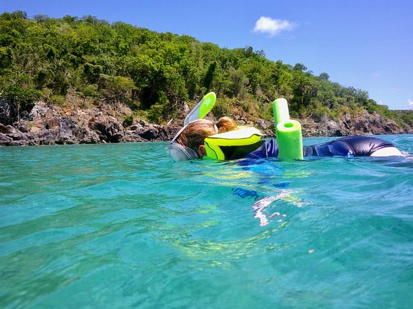 woman snorkeling with brightly colors float, swim vest and shirt in Tortola, British Virgin Islands