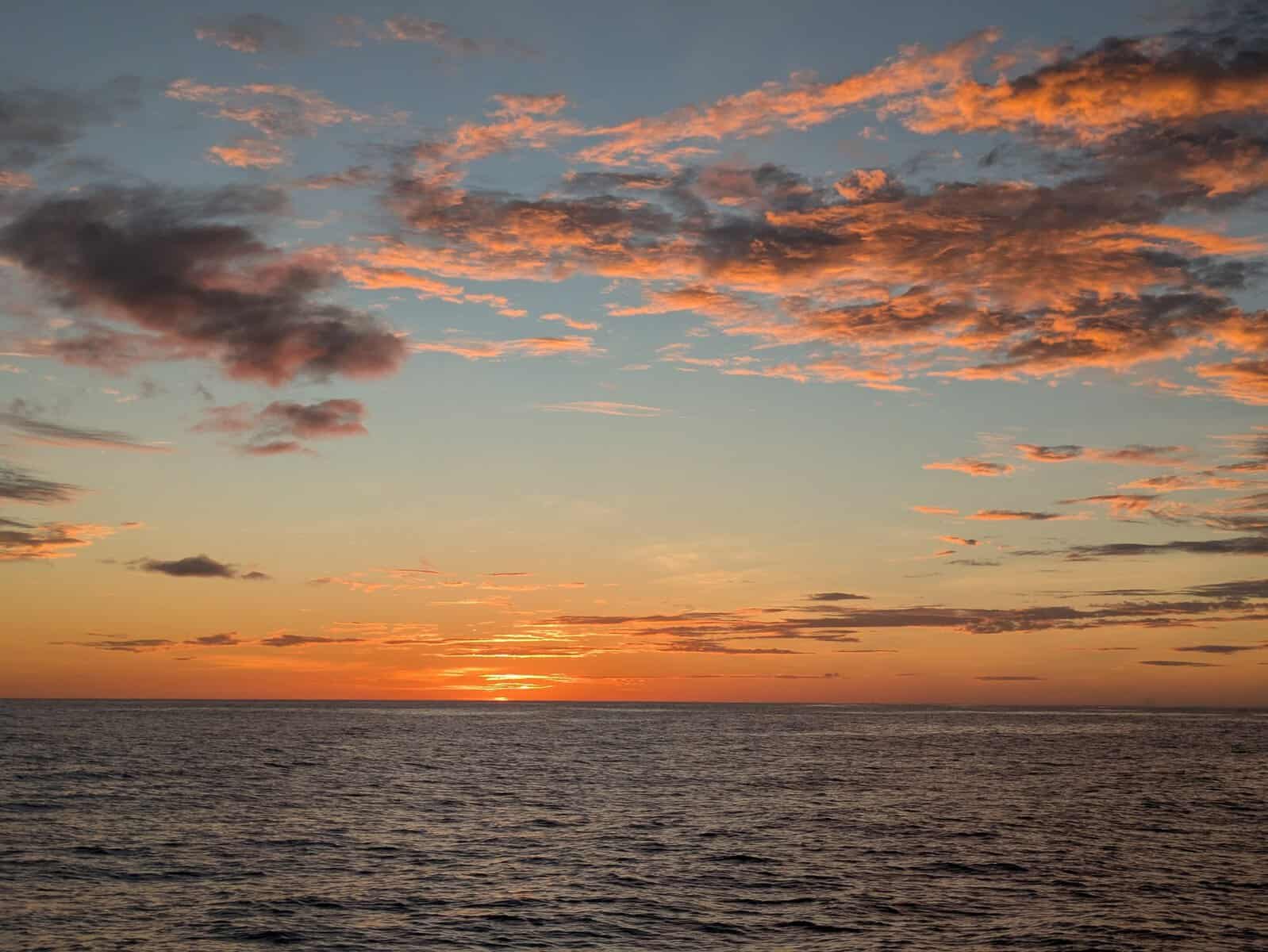 orange, green, blue and pink sunrise from Caribbean island looking out to sea