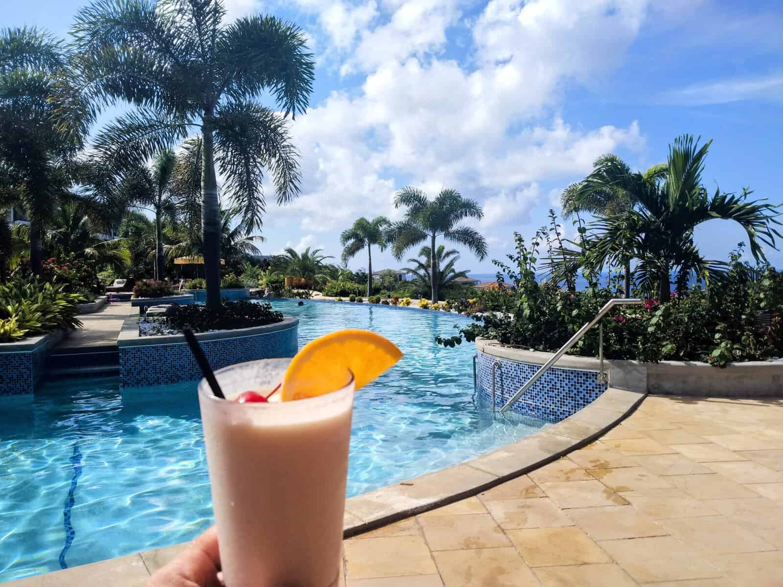 frozen drink with orange slice and palm trees, resort swimming pool, and Caribbean in background in December